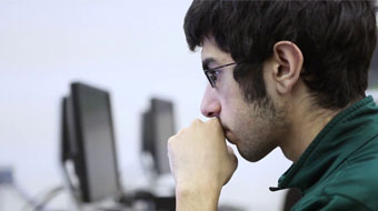 Computer Science student in deep thought on computer.