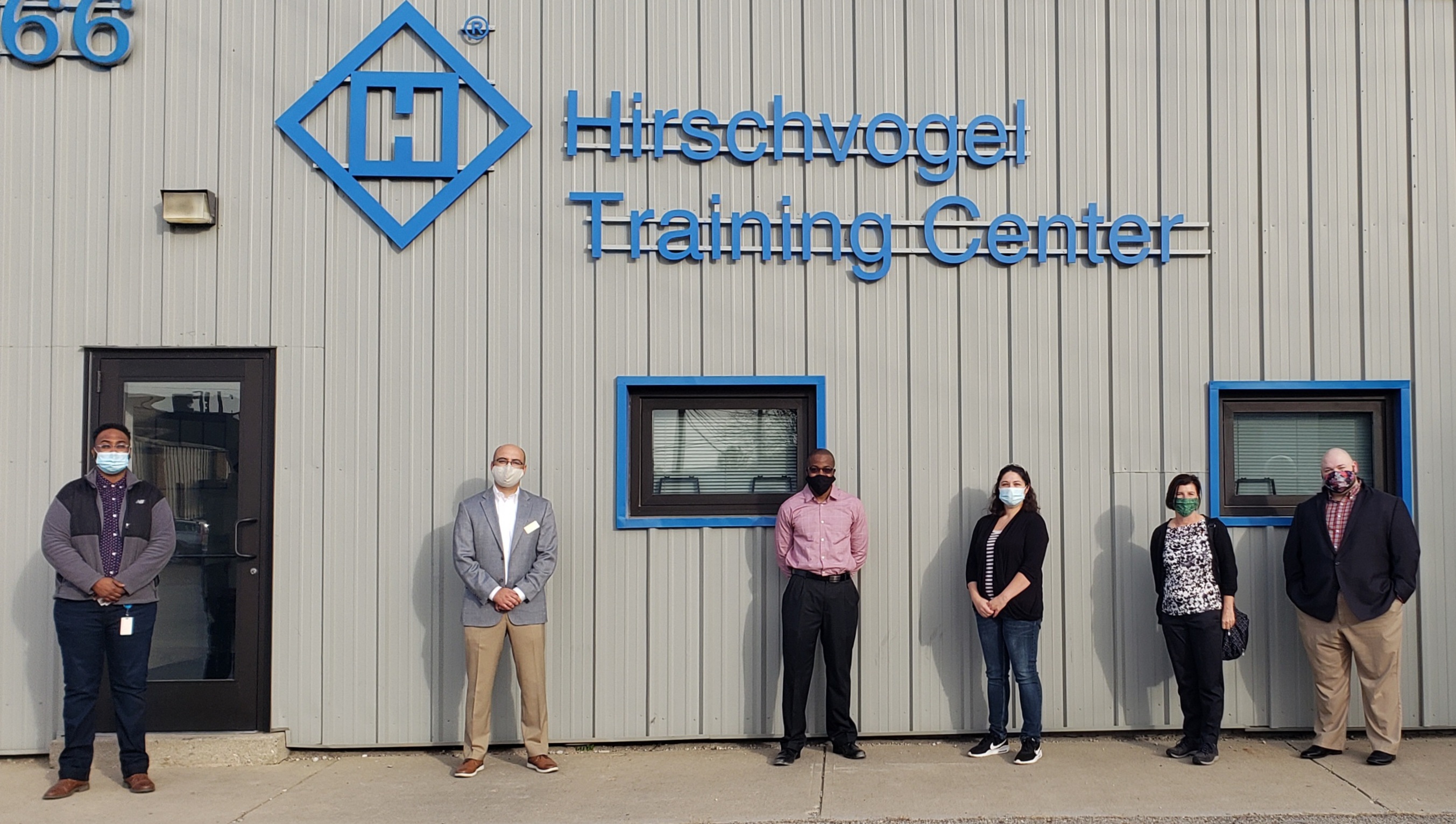 A picture of the two students, faculty member, and HR representatives from the company standing in front of the training center.