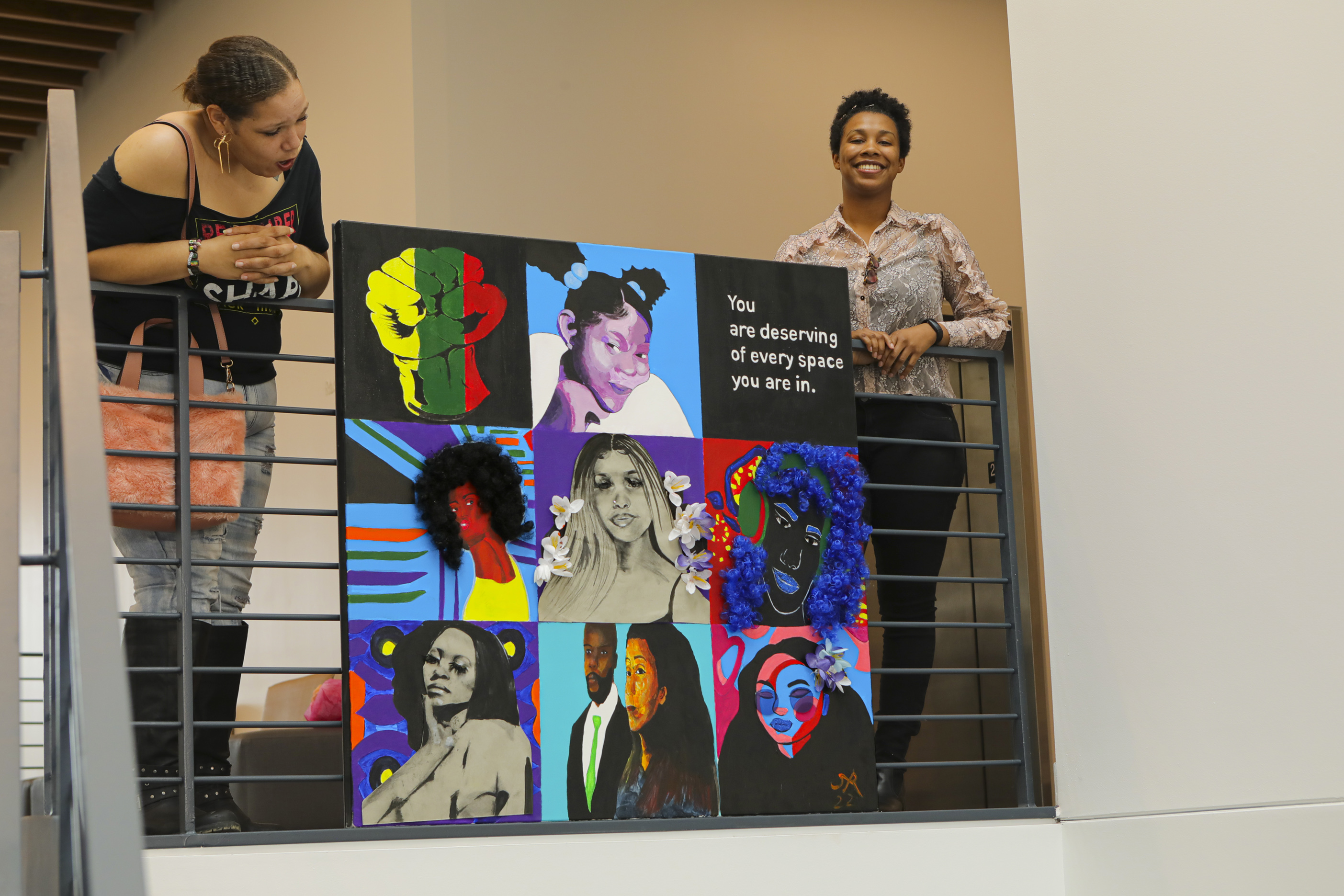 , Columbus State student Le'Ken Stokes, on the left, helps local artist Simone Robinson as she unveils her new artwork in the lobby of Mitchell Hall on April 12
