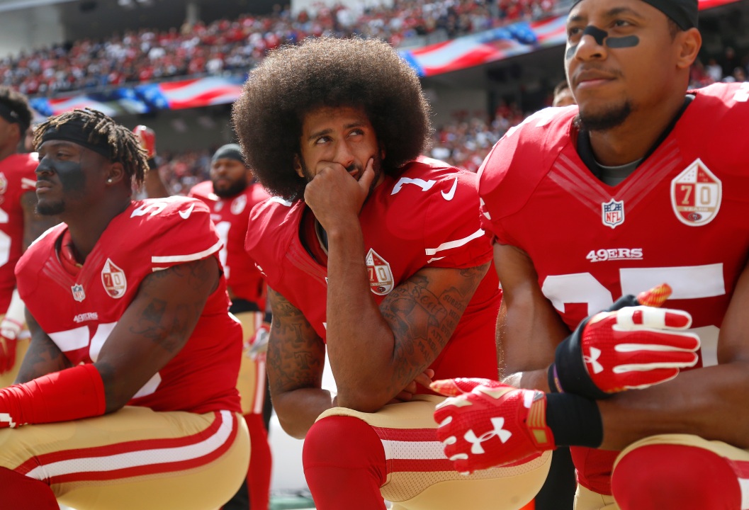 A picture of Colin Kaepernick kneeling at a football game. 