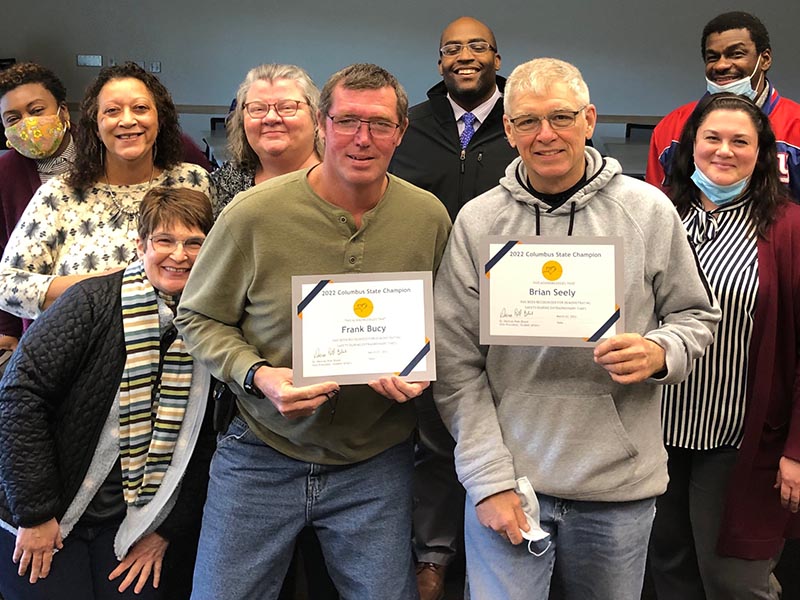 
Frank Bucy and Brian Seely (front center with certificates) were honored as "Champions." Others from the Delaware Campus Watch Party gathered around the pair.
 
