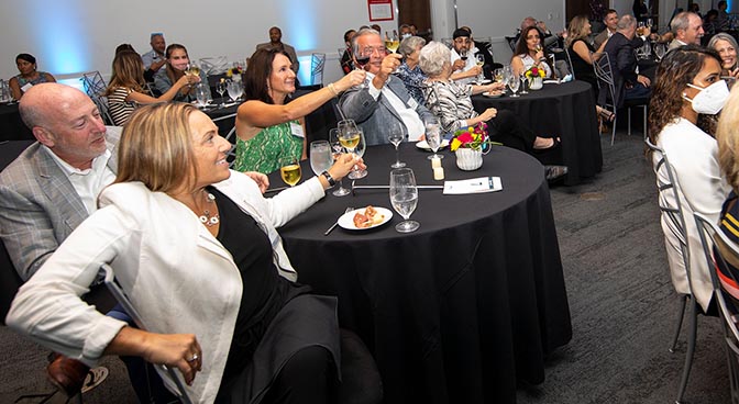 
On the left, David Miller, COO of Cameron Mitchell Restaurants (CMR), and Cameron Mitchell, on the right, founder and CEO of CMR, and their spouses, raise their glasses during a toast.
